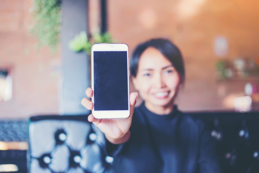 女性がスマートフォンを持ってこちらに向けている様子の画像