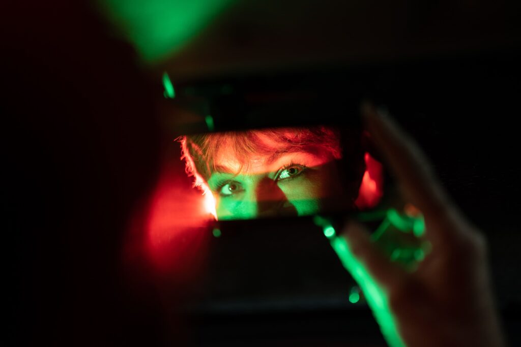 怪しい女性がスマートフォンを鏡の代わりにしてこちらを見ているイメージ画像